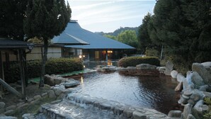 Un edificio japonés tradicional con un estanque, rodeado de rocas y follaje.