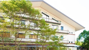 Un edificio de varios pisos con techo plano, amplios ventanales y un área exterior cubierta con plantas.