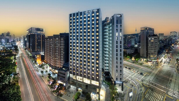 A modern high-rise building with multiple floors, large windows, and a prominent signage.