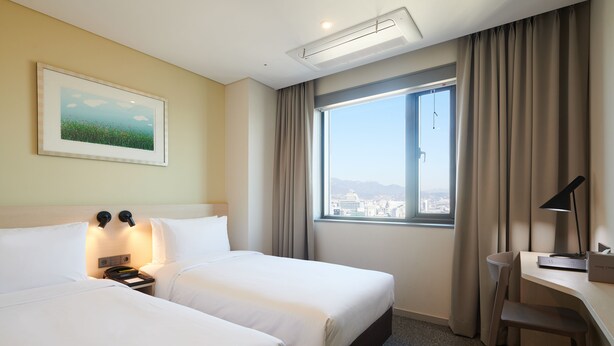 A hotel room with two beds, a desk, a chair, a large window with a view, and a painting on the wall. - NINE TREE BY PARNAS SEOUL DONGDAEMUN (Seoul)