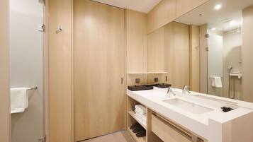 A modern bathroom with a wooden vanity, a large mirror, and a shower area.