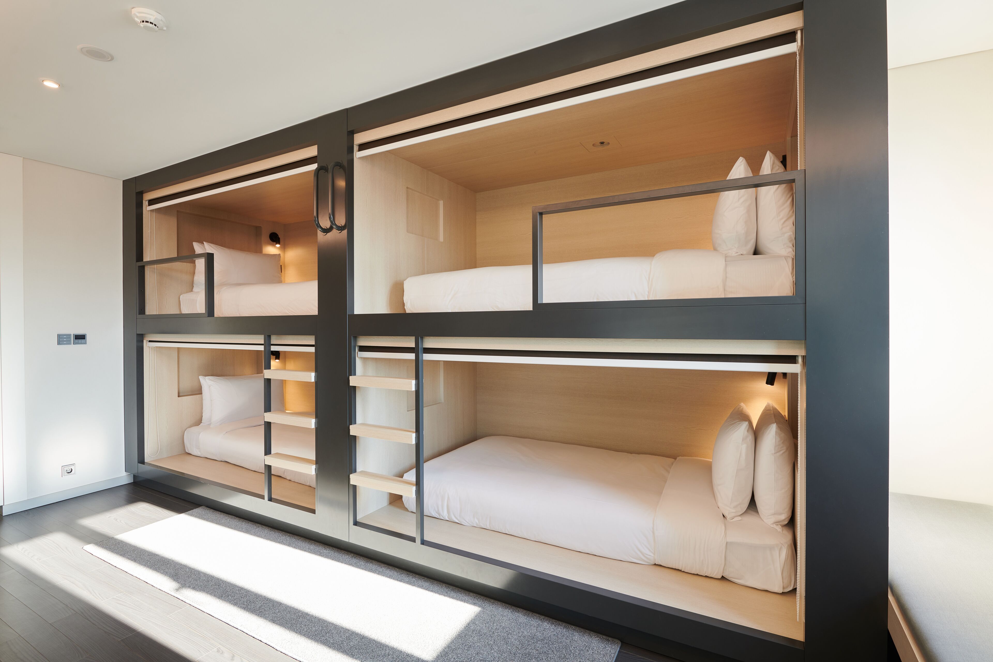 A modern, multi-level bunk bed room with built-in shelving and a minimalist design.