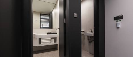 Un baño moderno con un lavamanos blanco, un espejo y un perchero para toallas.