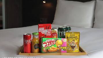 A tray with various food items and beverages on a bed.