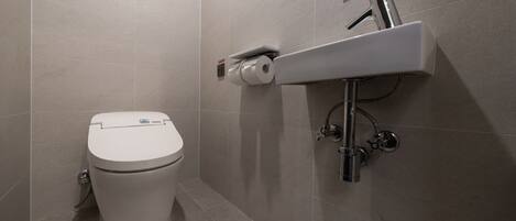Un baño moderno con inodoro, lavamanos empotrado y dispensador de papel higiénico.