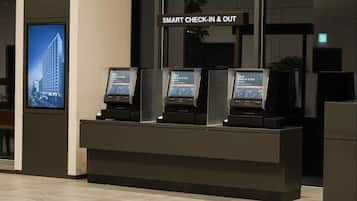 A check-in/out kiosk with a digital display and a sign above it reading "SMART CHECK-IN & OUT".
