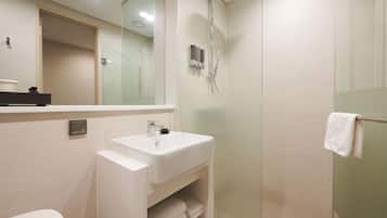 Une salle de bain moderne avec un lavabo blanc, une cabine de douche en verre et une serviette suspendue à un porte-serviettes.