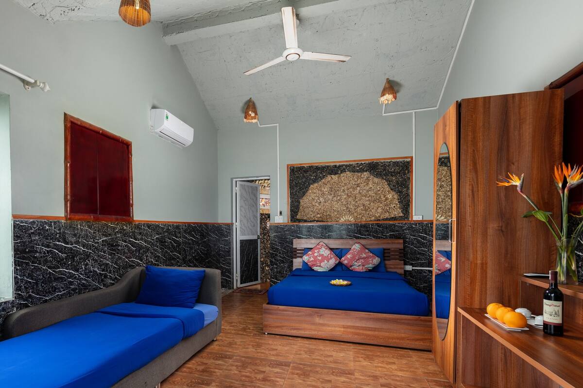 Une pièce comprenant un lit, un canapé, une armoire en bois et un ventilateur de plafond.