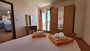 A hotel room with a bed, a desk, a mirror, and a view of the outside. - Apartment Adriana 1 for 4 people (Omisalj)