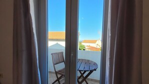 A view through a sliding glass door with a wooden chair and table outside. - Apartment Adriana 2  for 3 people (Omisalj)