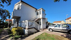 A two-story building with a white exterior, a staircase with white balusters, and a car parked in the driveway. - Apartment Adriana 2  for 3 people (Omisalj)