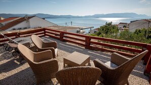 A terrace with wicker furniture overlooking a body of water and distant mountains. - 1 bedroom gorgeous apartment in Komarna (Komarna)