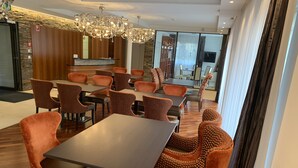 Un espace repas moderne avec des tables en bois et des chaises recouvertes d’un tissu orange.