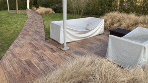 Un espace extérieur abrité avec une terrasse en bois, une table couverte et une chaise couverte.