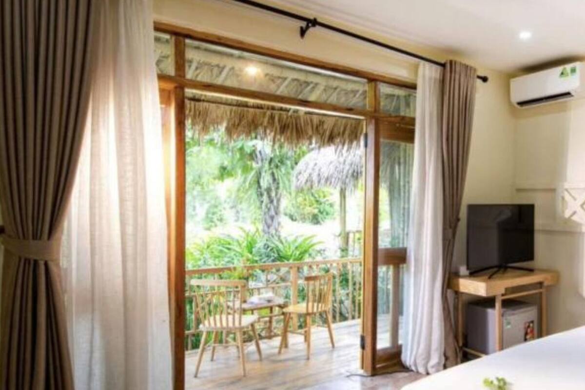 Un dormitorio con cama, televisión y balcón con sillas y mesa.