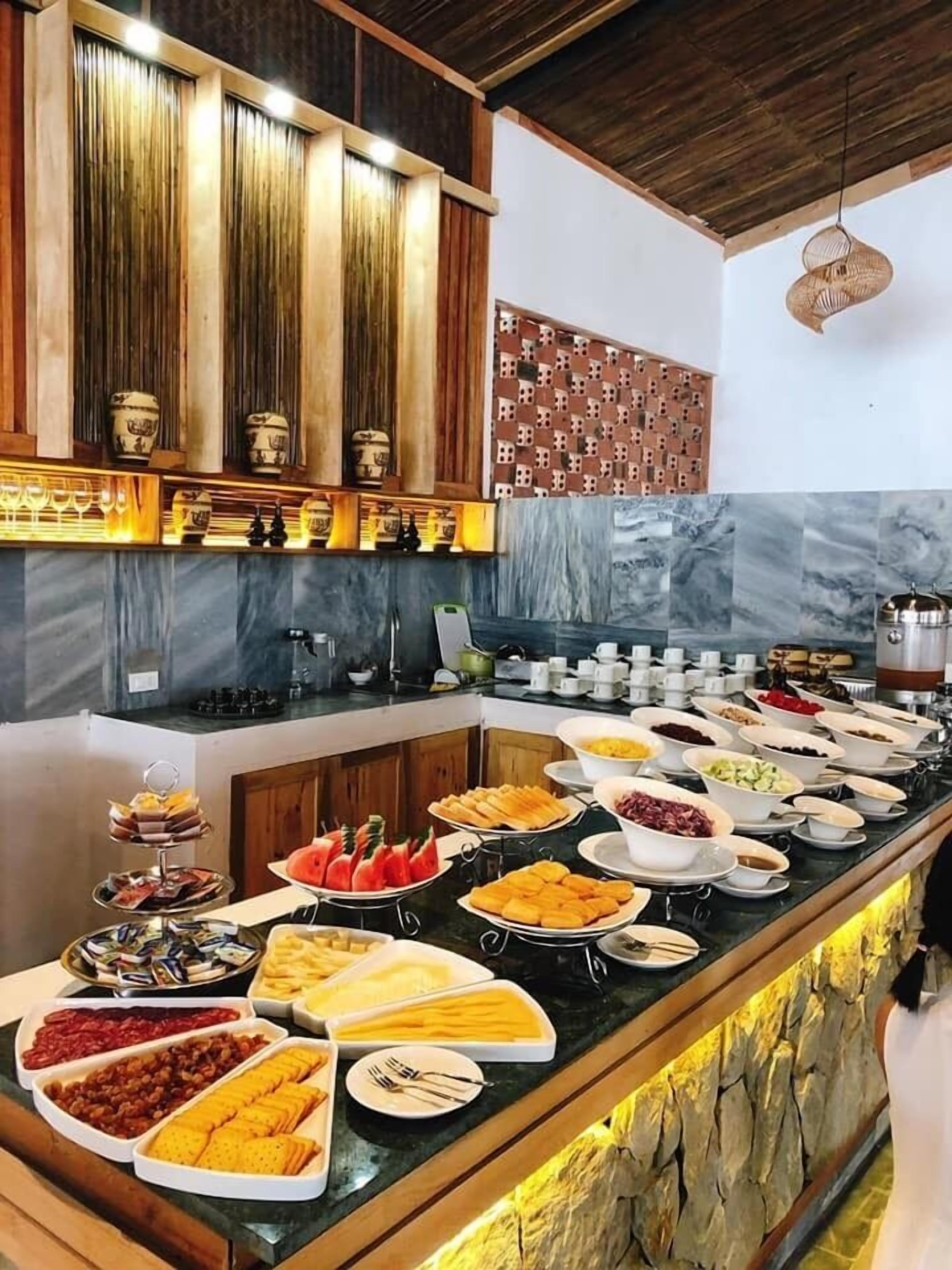 A buffet setup with various food items and a decorative wall with patterned tiles.