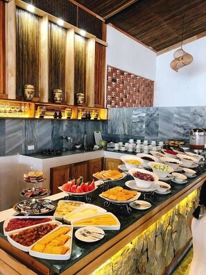A buffet setup with various food items and a decorative wall with patterned tiles. - Ba Khan Village Resort (Tan Mai)