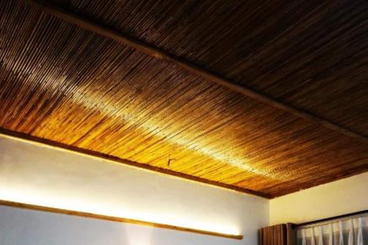 Habitación de hotel con dos camas, techo de madera, luz empotrada en la pared y una ventana con cortinas.