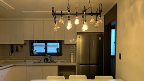 A modern kitchen with a central island, stainless steel appliances, and a dining area with white chairs.