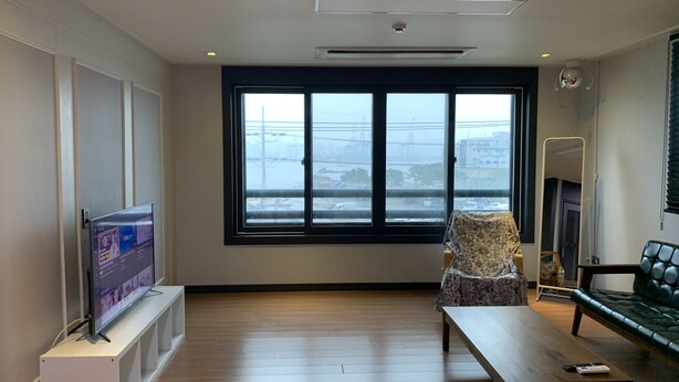 A modern living room with a large window, a flat-screen TV on a stand, a sofa, and a coffee table.