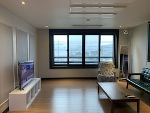 A modern living room with a large window, a flat-screen TV on a stand, a sofa, and a coffee table.