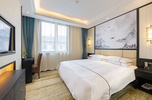 Habitación de hotel con una cama grande, un escritorio, una silla, un televisor y un cuadro en la pared.
