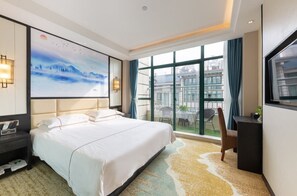 A hotel room with a large bed, a desk, a chair, a TV, and a painting on the wall. - Yiwu Luck Bear Hotel (Jinhua)