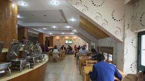A cafeteria with buffet-style food stations, wooden tables, and chairs. - Yiwu Luck Bear Hotel (Jinhua)