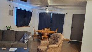 A living room with a ceiling fan, a sofa, a coffee table, a chair, and a dining table with chairs. - Shaggy Moos Apartment  (Bloomfield)