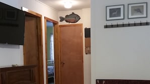 A living room with a fireplace, a round table, a television mounted on the wall, and a door leading to another room. - Escape on the river (French Creek)
