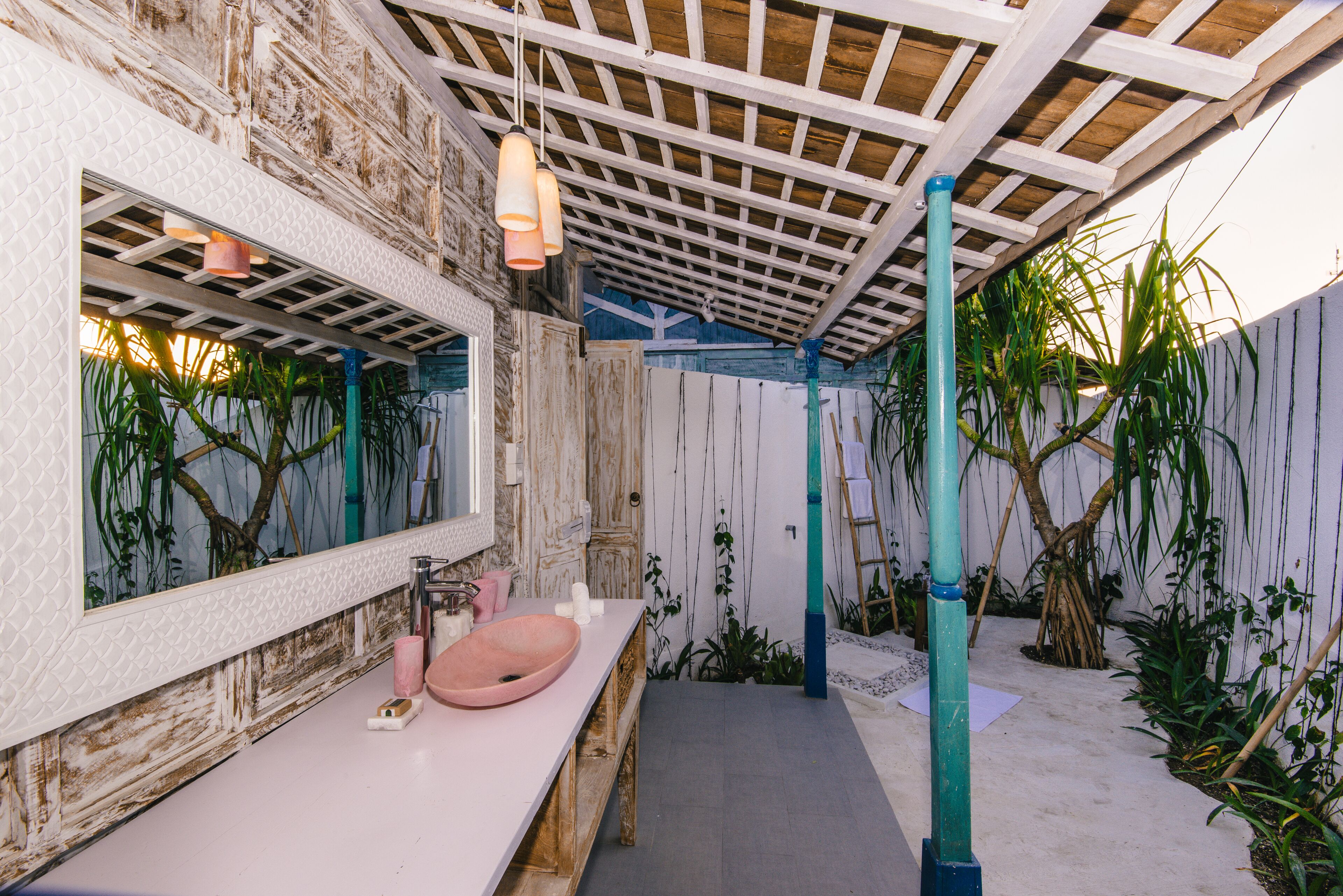 A bathroom with a wooden vanity, a pink sink, and a large mirror.