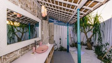 A bathroom with a wooden vanity, a pink sink, and a large mirror.