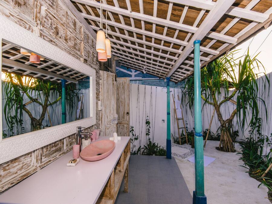 A bathroom with a wooden vanity, a pink sink, and a large mirror.