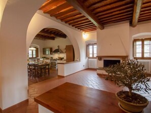 Uma sala de estar espaçosa com lareira, uma área de jantar e uma cozinha visíveis através de um arco.