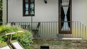 A patio with two lounge chairs, a small table, and a stone wall.