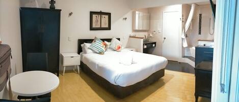 Una habitación de hotel con cama, mesita de noche, silla y una pequeña mesa redonda.