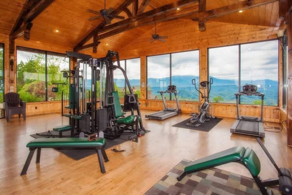 A gym with exercise equipment, large windows, and a view of mountains.