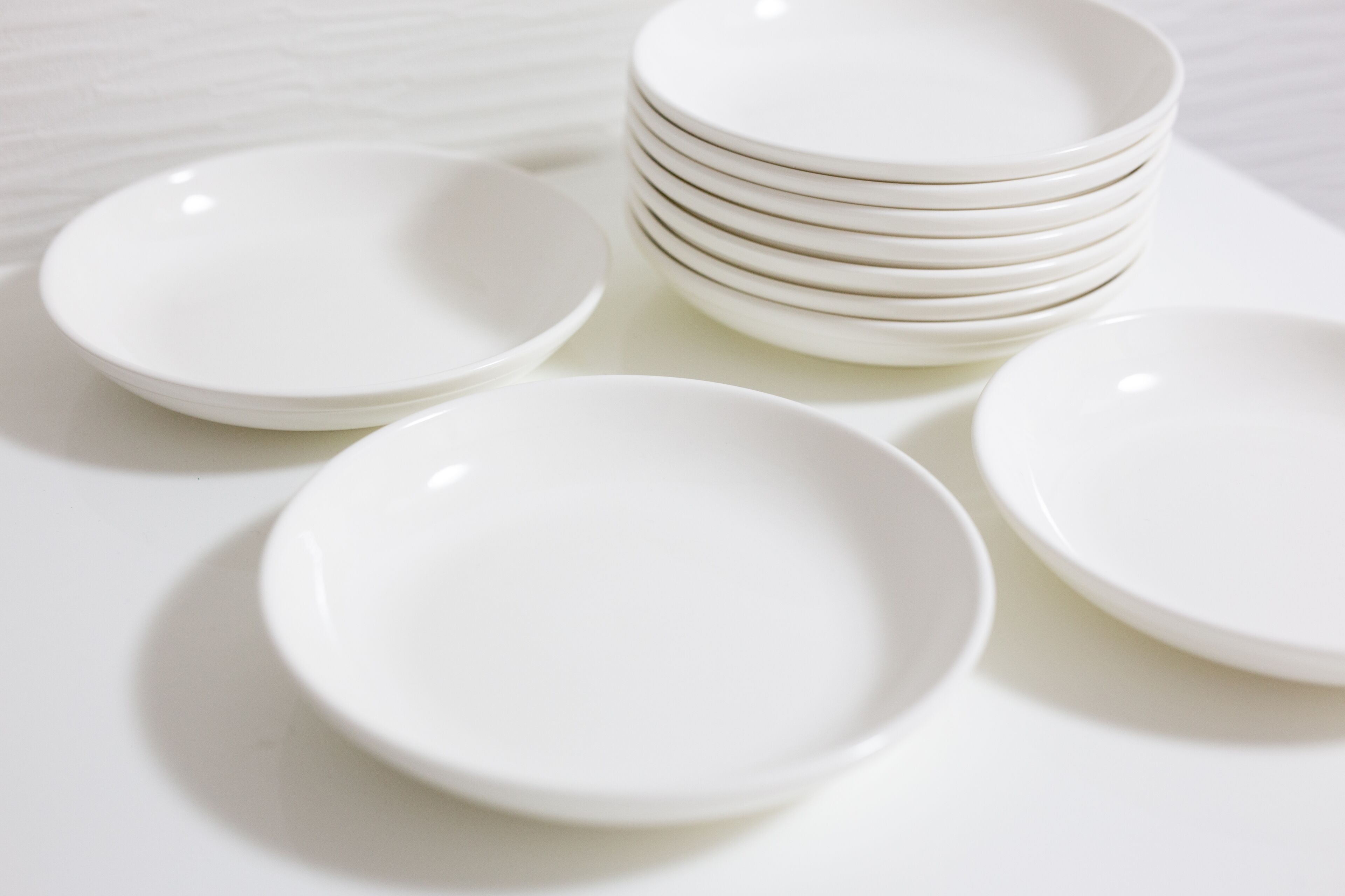 Una pila de platos blancos sobre una superficie blanca.