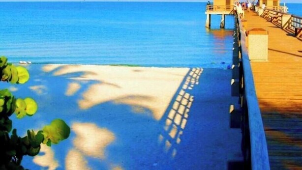 A pier extending into a calm sea with a clear sky. - 555 Royal Palm Villa | Luxury Heated Pool Home (Naples)