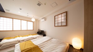 Ein Hotelzimmer mit zwei Betten, einem traditionellen japanischen Shoji-Bildschirm und einer modernen Lampe.