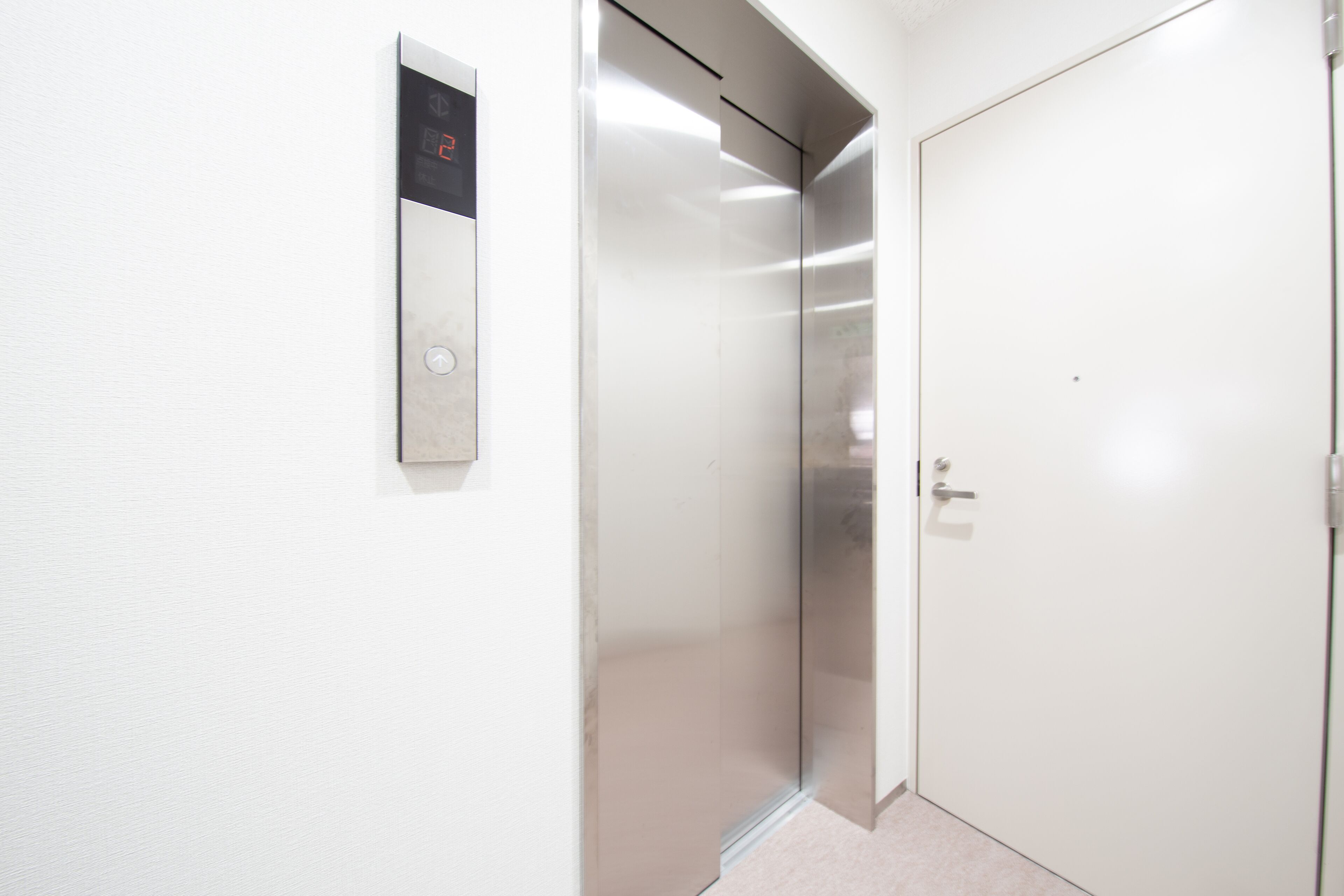 A modern elevator with a digital display and a plain white door.