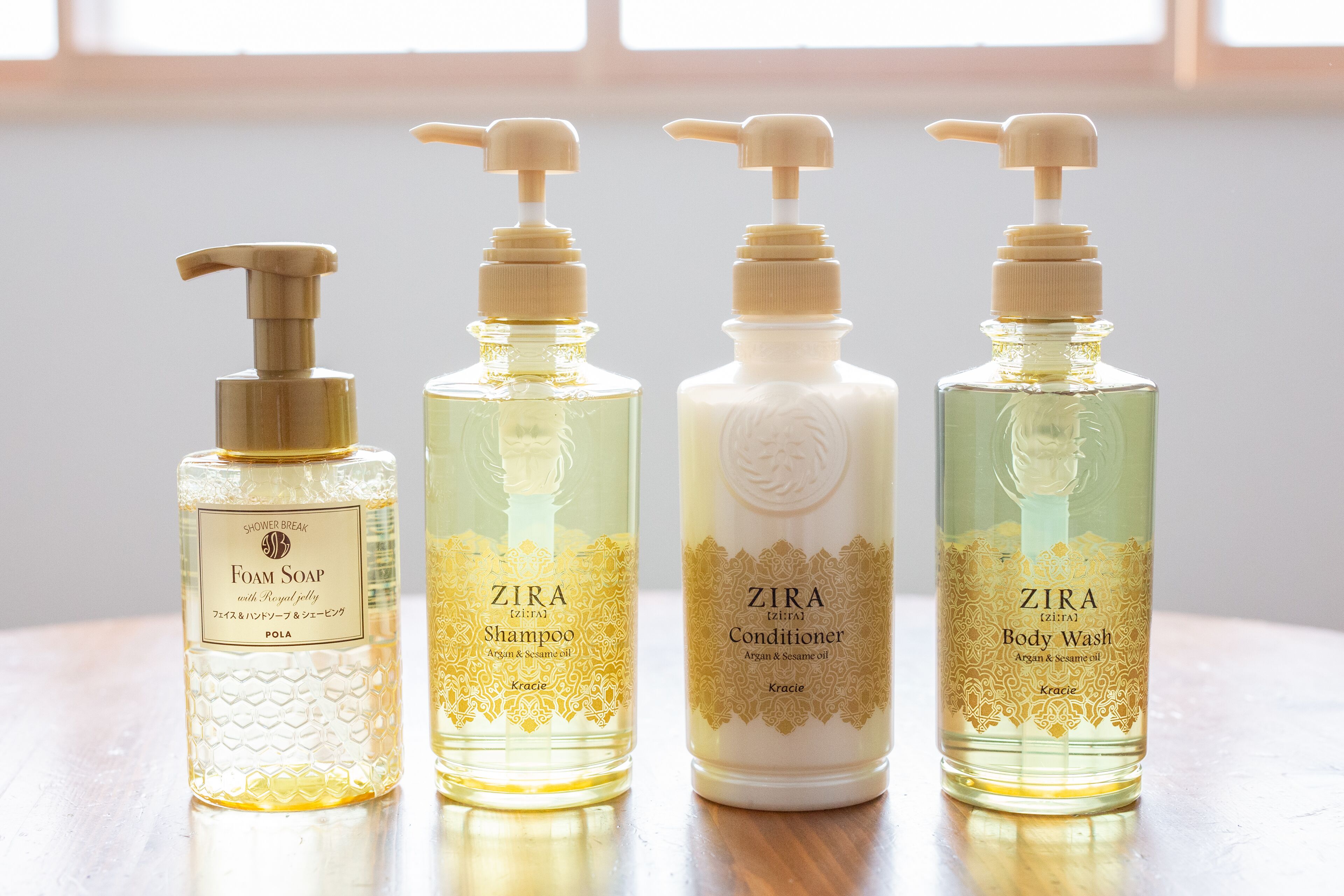 Four bottles of ZIRA body wash and shampoo on a wooden surface.