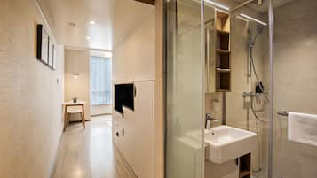 A modern bathroom with a glass shower enclosure, a white sink, and a wooden vanity.