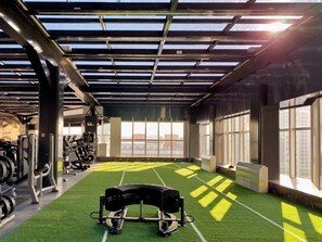 Uma academia com grama sintética, equipamentos de exercício e grandes janelas.