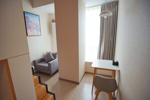 Una sala de estar moderna con un sofá, una mesa de comedor y una escalera que lleva a otra habitación.