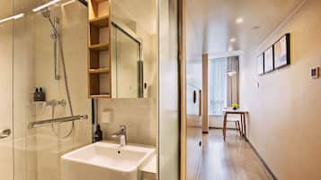 Une salle de bain moderne avec une douche à parois de verre, un lavabo blanc et un meuble-lavabo en bois.