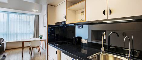 Cocina moderna con encimera negra, pileta de acero inoxidable y muebles blancos.