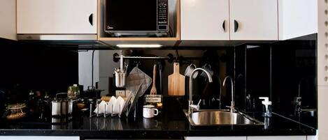 A compact kitchen with a microwave, sink, and dishwasher.