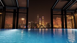 Piscina interna com vista para a cidade à noite.