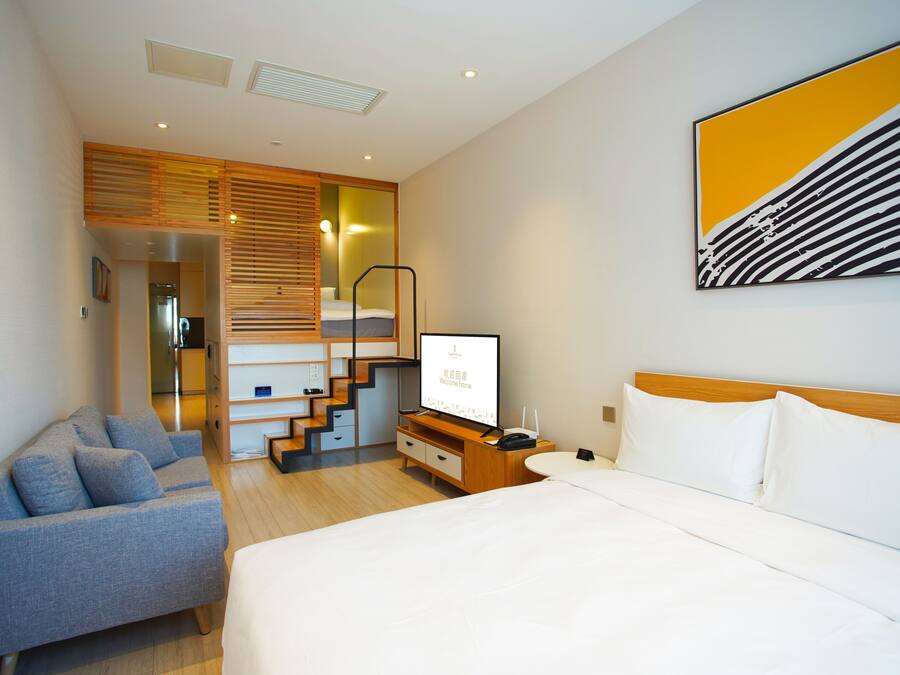 Et moderne hotelværelse med seng, sofa, fjernsyn og trappe til en etage ovenover.